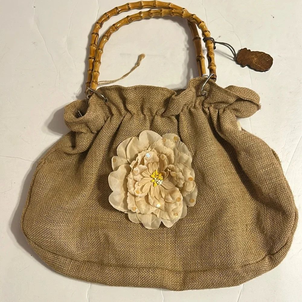 Tan purse made from burlap with beige flower and bamboo handles